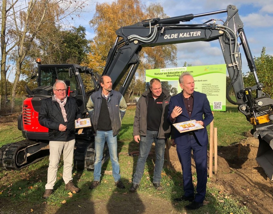 Een gemengde groep mensen van IVN en Olde Kalter die voor een kleine shovel staan